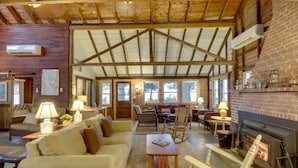 A cozy living room with a fireplace, wooden beams, and comfortable seating. - Rustic Cliff-top Cabin at the Tip of Lake Champlain's Barney Point (Colchester)
