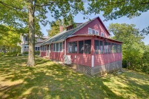 A red wooden house with a large porch and a fenced yard.
