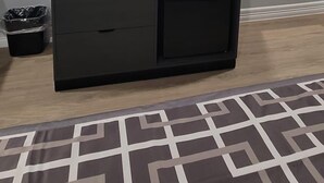 A room with a black entertainment unit, a microwave, and a small trash bin. - Platinum inn (Katy)