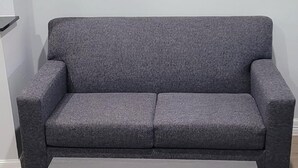 A grey sofa and a dark wooden coffee table in a room with light wooden flooring. - Platinum inn (Katy)