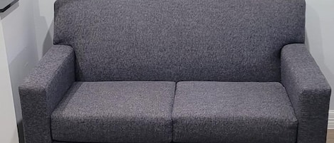 Un sofá gris y una mesa de centro de madera oscura en una habitación con suelo de madera clara.