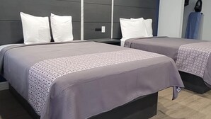 A hotel room with two beds, a modern headboard, and a wooden floor. - Platinum inn (Katy)