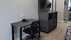A modern room with a desk, chair, TV, and a bed. - Platinum inn (Katy)