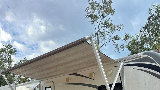 A recreational vehicle with a covered area and a wooden deck.