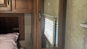A bedroom with a bed, wooden cabinets, a mirror, and a door leading to a balcony.