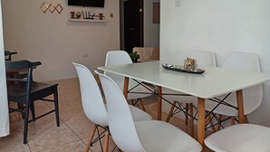 A dining area with a white table and chairs, a ceiling fan, and a flat-screen TV mounted on the wall. - Your-Holiday home fortuna arenal with swimming pool (La Fortuna)
