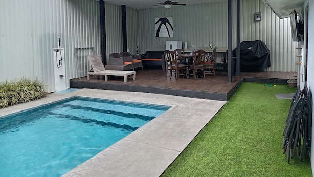 A backyard with a swimming pool, a covered patio area with outdoor furniture, and a small lawn. - Your-Holiday home fortuna arenal with swimming pool (La Fortuna)