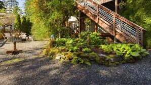 Una scala in legno conduce a un pontile di legno con ringhiere, immerso nel verde e affiancato da un vialetto sterrato.