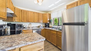 Una cucina moderna con mobili in legno, piani in granito, elettrodomestici in acciaio inossidabile e una finestra che lascia entrare luce naturale.