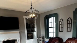 Un salon avec une cheminée, des canapés en cuir, une table basse et un lustre.