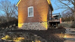 Un bâtiment en briques avec des fondations en pierre, une fenêtre et un mur en pierre agrémenté de luminaires.