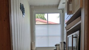 A narrow kitchen with wooden cabinets, a built-in oven, and a window with blinds. - Vacation home with outdoor sauna in the Thuringian Forest (Schleusegrund)