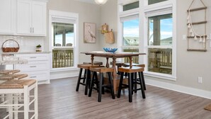 A spacious kitchen with white cabinets, a wooden dining table, and large windows. - 3 Bdr/3 Bth, King Bed, No Fees (Bolivar Peninsula)