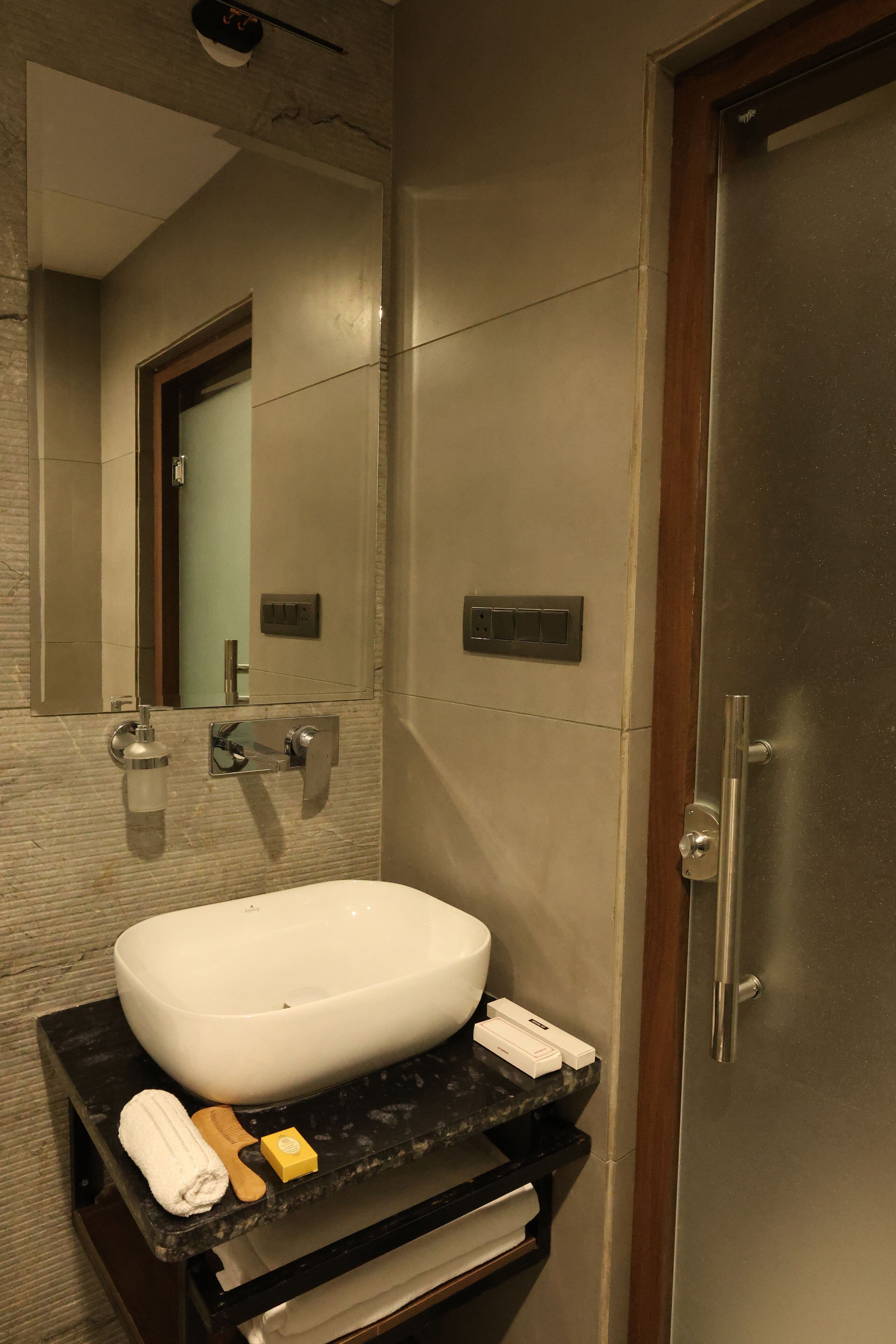 Un baño moderno con un lavabo grande, espejo y puerta.