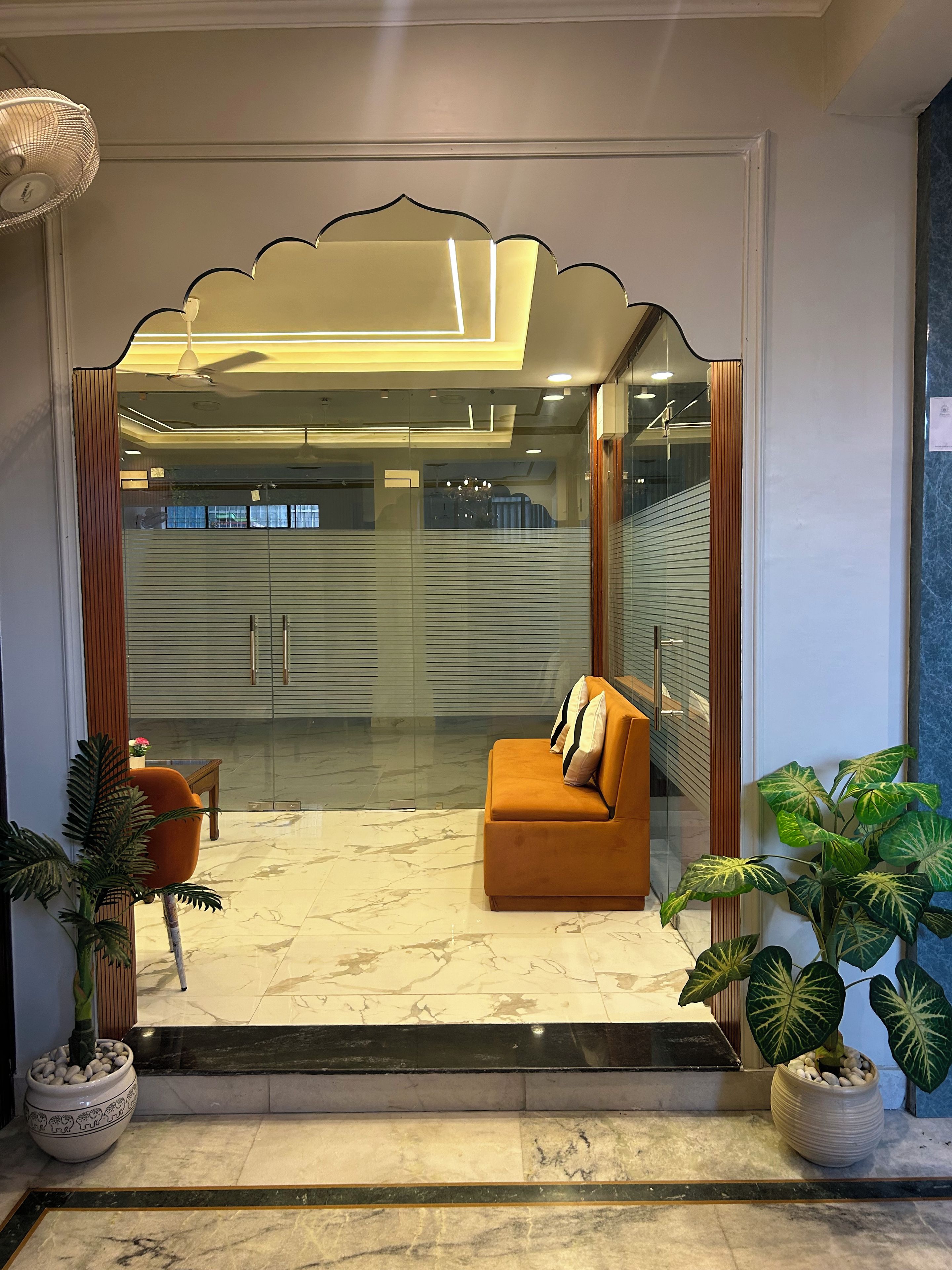 Un interior moderno con un sofá, una planta en maceta y un ventanal de vidrio que da a un balcón.
