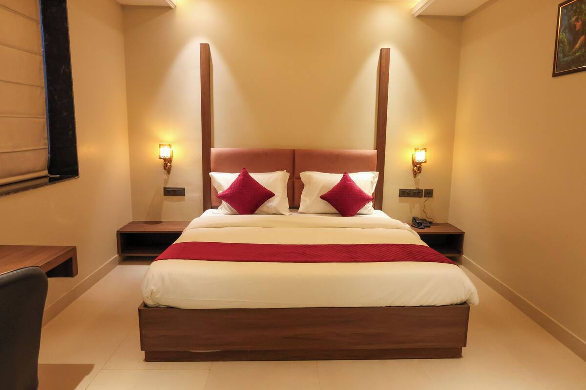 Une chambre d’hôtel bien aménagée, avec un grand lit, deux tables de chevet et une chaise.