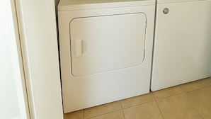 A compact, white laundry room with a single door and a small control panel.