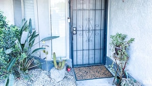 A house with a metal gate, a doormat, and potted plants.