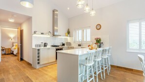 Una cocina moderna con una isla central, taburetes de bar e iluminación colgante.