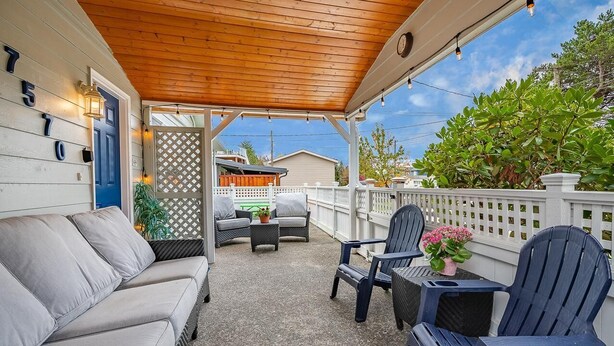A covered patio with a wooden ceiling, outdoor furniture, and a view of the neighborhood.