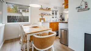 A modern kitchen with white brick walls, a wooden dining table, and wicker chairs.