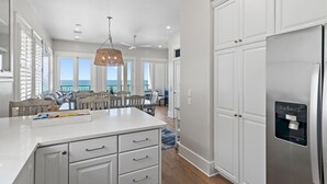 A modern kitchen with white cabinetry, a stainless steel refrigerator, and a water dispenser.