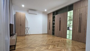 A spacious room with wooden flooring, built-in wardrobes, and a television on a wooden stand. - Fera (Belgrade)