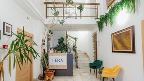 A reception area with a sign reading "FERA," a staircase, and two chairs, one green and one yellow. - Fera (Belgrade)