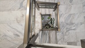 A view from a balcony looking down at a marble staircase with a glass railing and a small plant on the floor. - Fera (Belgrade)