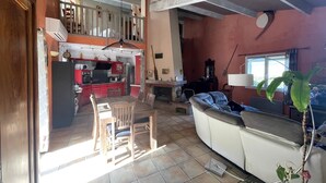 A spacious living area with a dining table and chairs, a sofa, and a kitchen in the background.