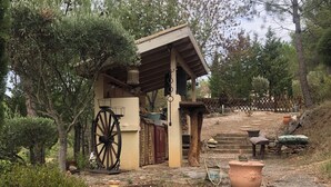 A rustic outdoor setting with a small wooden structure, stone walls, and various garden items.
