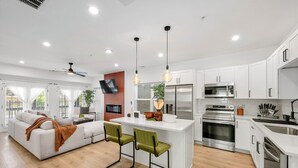 A modern kitchen with white cabinets, stainless steel appliances, and a central island with bar stools.