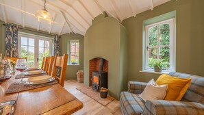 Una habitación acogedora con una mesa de madera dispuesta para comer, una chimenea y un sofá cómodo con cojines.