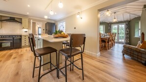 Una cocina amplia con una isla central, suelo de madera y luminarias modernas.