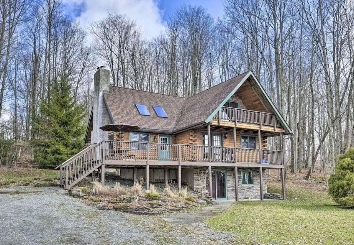 A cabin with a balcony, a chimney, and solar panels.