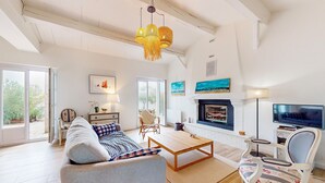 A spacious living room with a sofa, a coffee table, and a TV. There is a fireplace and a dining area with a table and chairs. - Lovely home in L'épine with WiFi (L'épine)