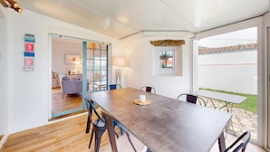 A dining area with a long table, chairs, and a view of a garden through a glass door. - Lovely home in L'épine with WiFi (L'épine)