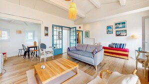 A spacious living room with a wooden coffee table, a grey sofa, and a red bench. There are two doors leading to other rooms, and the walls are adorned with framed artwork. - Lovely home in L'épine with WiFi (L'épine)