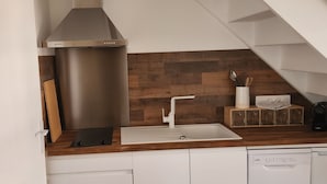 A modern kitchen with a stainless steel range hood, a wooden backsplash, a white sink, and a built-in dishwasher. - Elegant duplex, 75 meters from the Cathedral. Tourist or business stays (Amiens)