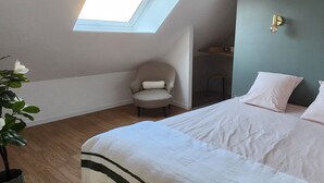 A bedroom with a bed, a chair, a skylight, and a wall-mounted light fixture. - Elegant duplex, 75 meters from the Cathedral. Tourist or business stays (Amiens)