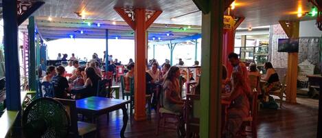 A restaurant with wooden flooring, tables, and chairs.