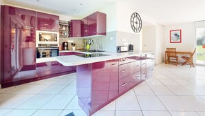 A modern kitchen with a central island, built-in appliances, and a dining area with a wooden table and chairs. - Beautiful home in Rubercy with sauna (Rubercy)
