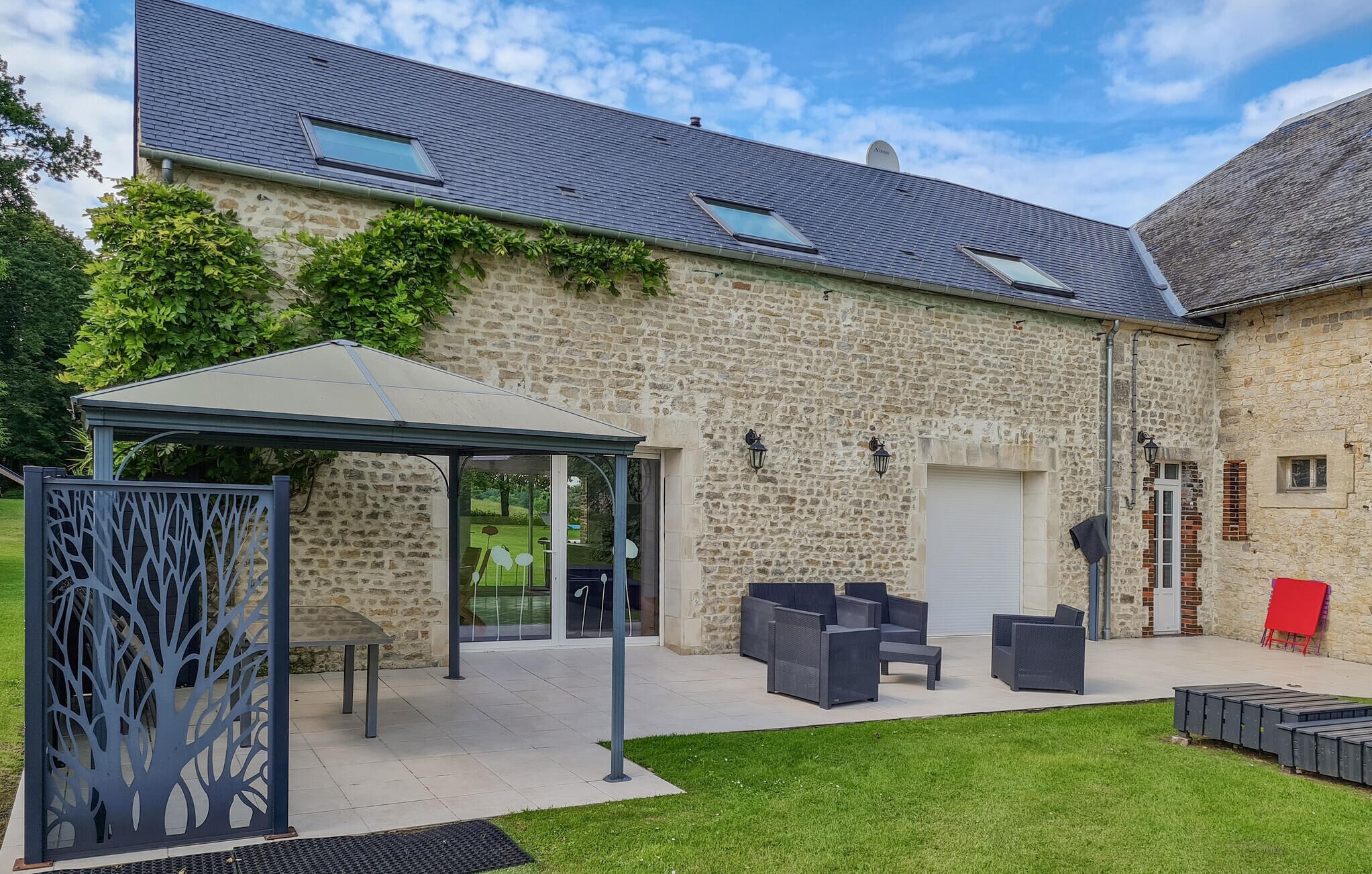 A stone building with a covered patio area, outdoor seating, and a garden.