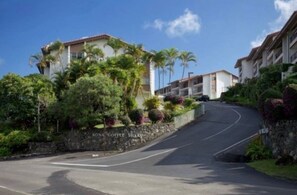 Un bâtiment doté d’un mur en pierre et d’une végétation luxuriante, portant l’inscription « KONA COFFEE VILLAS ».