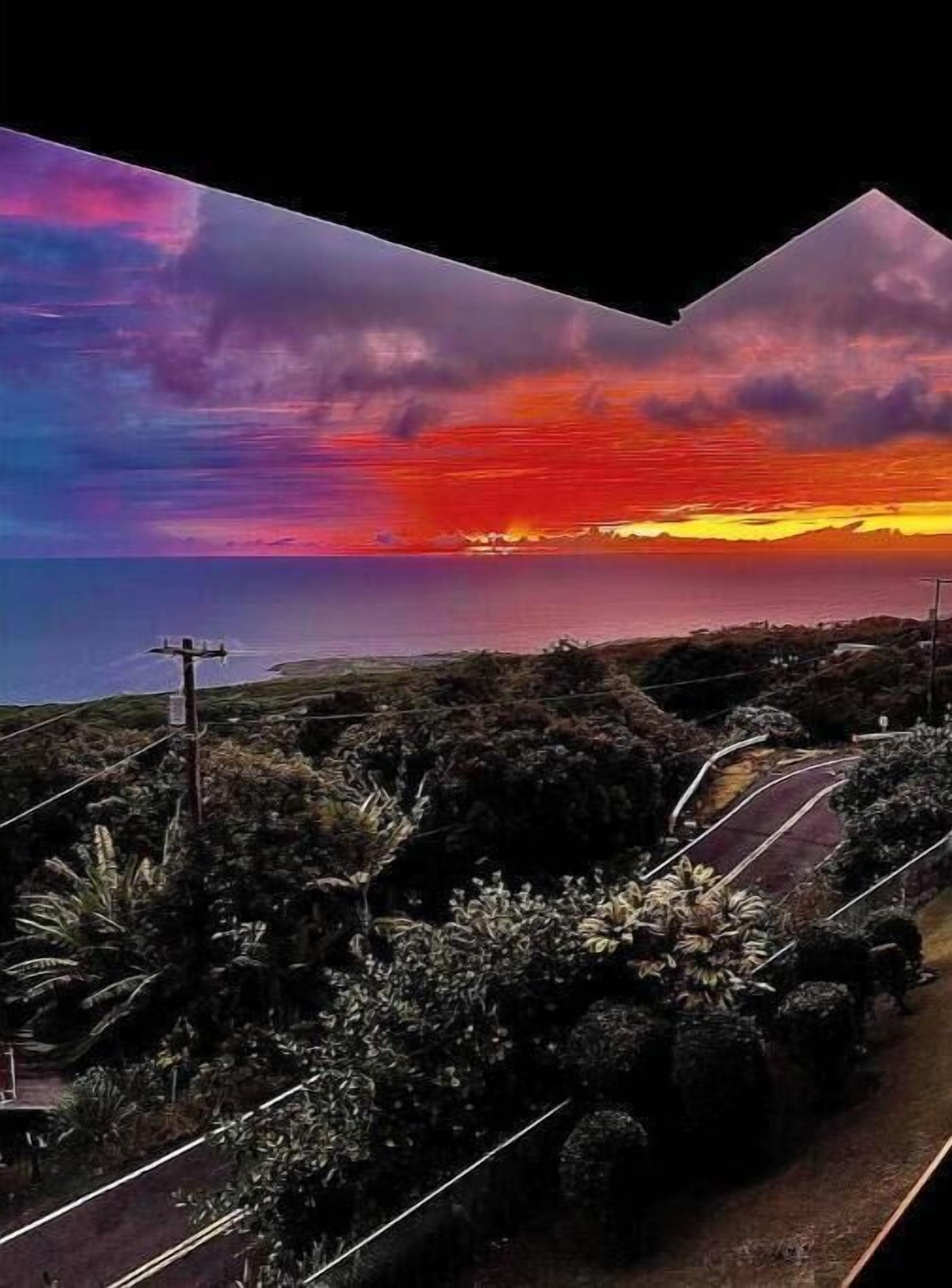 Carretera costera con vista al atardecer, rodeada de vegetación y postes de electricidad.