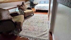 Une chambre confortable située dans les combles, avec un plafond en bois, un lit, une chaise et un bureau.