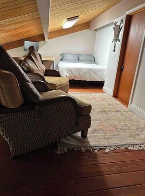 Una habitación acogedora con techo de madera, un sofá, una cama y una mesita.