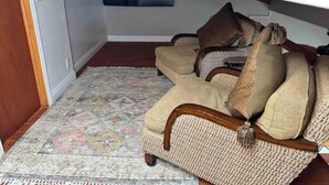 Un salon chaleureux avec un tapis à motifs, un canapé agrémenté de coussins et un téléviseur fixé au mur.