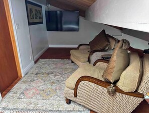 Una sala de estar acogedora con un tapete estampado, un sofá con cojines y un televisor montado en la pared.