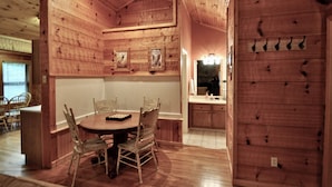 A wooden interior with a dining table and chairs, a kitchen area with wooden cabinets, and a wall-mounted coat rack. - Trails End, your own private retreat in the Smokies! (Townsend)